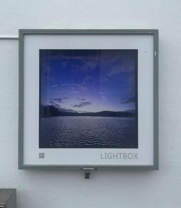A photograph of the ocean and hills in the horizon, placed inside the Thistle Hall Lightbox