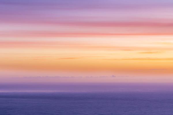 Sunrise at Sea by Emma Hissey is a serence photograph of the ocean with the horizon hazily in the distance with beautiful dreamy pink and blue colours