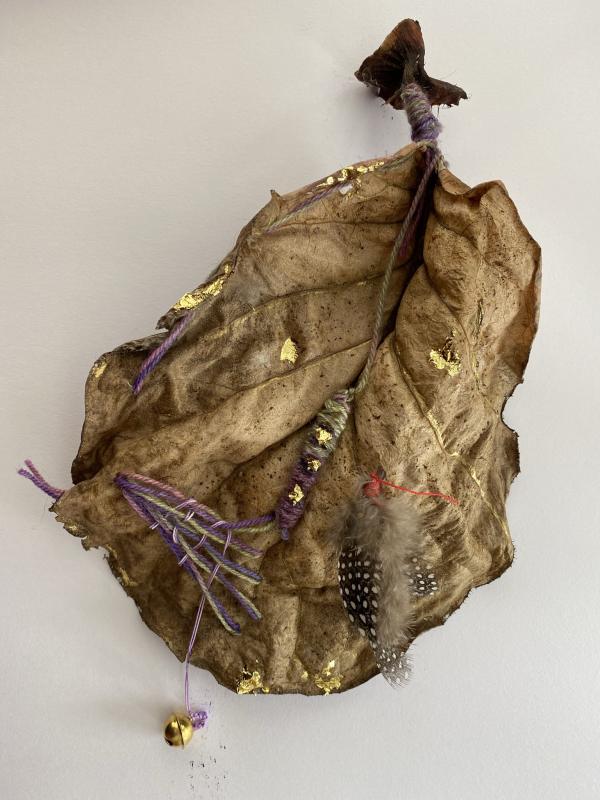 A leaf with crafted additions such as gold leaf and string