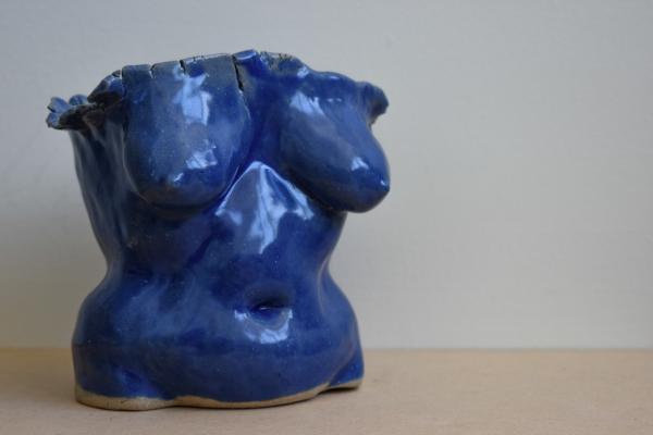 Blue ceramic torso by Lilly Rhind. The figure is heavy-breasted and curvy, it looks like a comfortably lived in body.