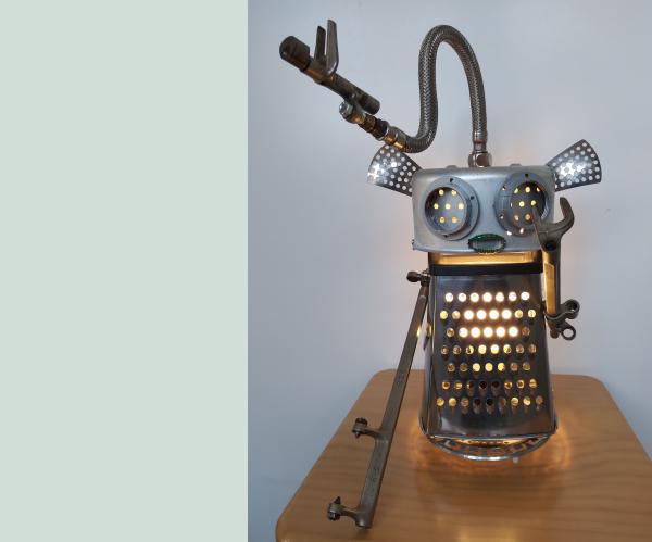 Friendly robot lamp - cheese grater body with metal pipe and window latch limbs. Artist Stuart Gray.